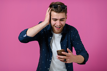 Image showing a young man wearing a blue shirt and sunglasses using a smartphone