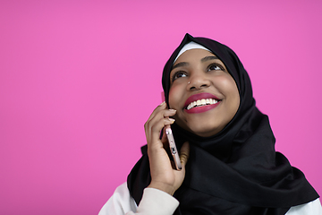 Image showing afro woman uses a cell phone in front of a pink background
