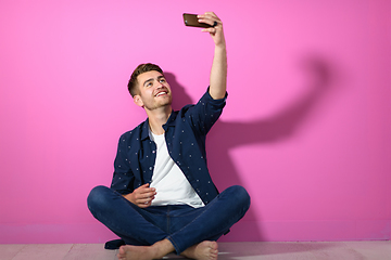 Image showing man sitting on the floor of the house and using the phone