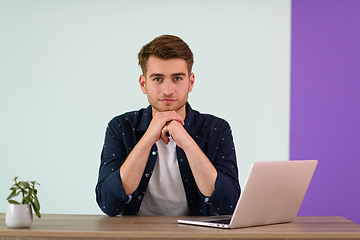 Image showing Smiling young man freelancer using laptop studying online working from home