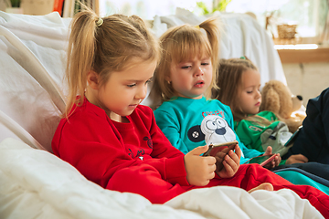 Image showing Little girls in soft warm pajamas playing at home