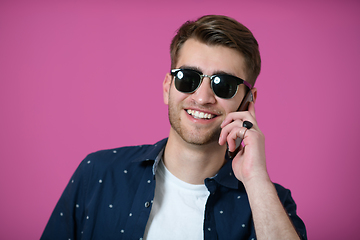 Image showing a young man wearing a blue shirt and sunglasses using a smartphone