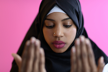 Image showing Modern African Muslim woman makes traditional prayer to God, keeps hands in praying gesture, wears traditional white clothes