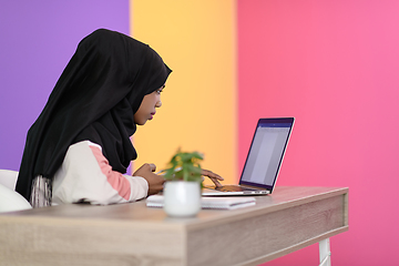 Image showing afro girl wearing a hijab is disappointed and sad sitting in her home office and using a laptop