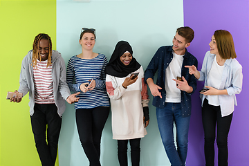 Image showing diverse teenagers use mobile devices while posing for a studio photo in front of a pink background