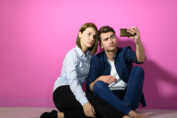 Image showing a happy young couple sitting on the floor in the house and making selfie