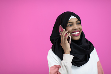 Image showing afro woman uses a cell phone in front of a pink background