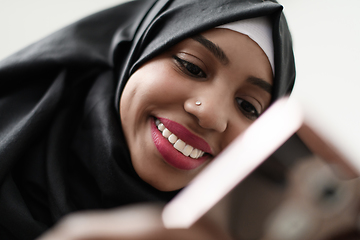 Image showing afro girl uses a cell phone and browses social media during a pandemic