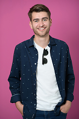 Image showing a portrait of a young man wearing a blue shirt and posing in front of a pink background 