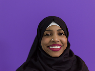 Image showing portrait of african muslim woman wearing hijab and traditional muslim clothes posing in front of purple background