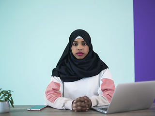 Image showing afro girl wearing a hijab thoughtfully sits in her home office and uses a laptop