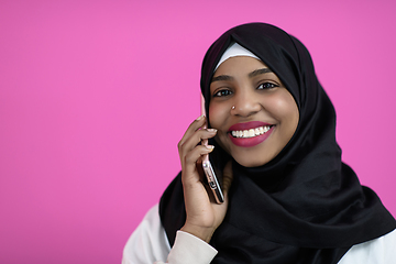 Image showing afro woman uses a cell phone in front of a pink background