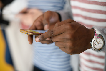 Image showing diverse teenagers use mobile devices while posing for a studio photo in front of a pink background