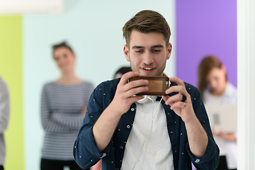 Image showing guy with the beautiful smile in the blue attractive shirt i use my cell phone and headphones