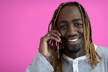 Image showing afro guy uses a phone while posing in front of a pink background.