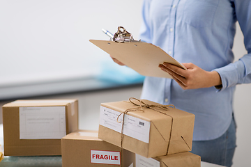 Image showing woman with parcels and clipboard at post office