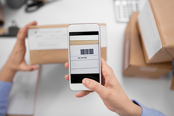 Image showing hands with smartphone scans barcode on parcel box
