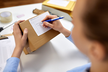 Image showing close up of woman filling postal form at office