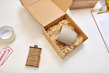 Image showing parcel with straw filler and mug at post office