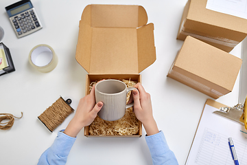 Image showing hands packing mug to parcel box at post office