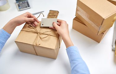 Image showing hands tying name tag to parcel box at post office