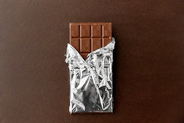 Image showing chocolate bar in foil wrapper on brown background