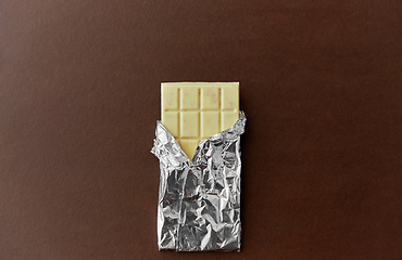 Image showing white chocolate bar in foil wrapper on brown