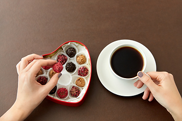 Image showing hands, candies in heart shaped box and coffee cup