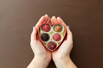 Image showing hands with candies in heart shaped chocolate box