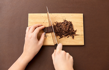 Image showing hands chopping chocolate chips on wooden board