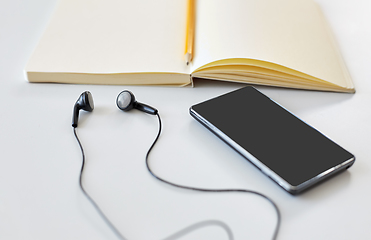 Image showing earphones, smartphone and notebook with pencil