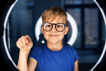 Image showing boy in glasses over illumination in dark room