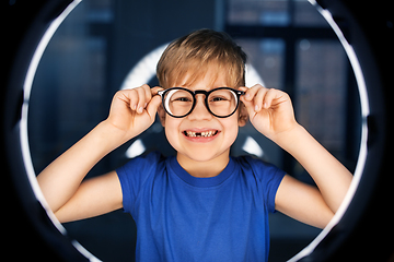 Image showing boy in glasses over illumination in dark room