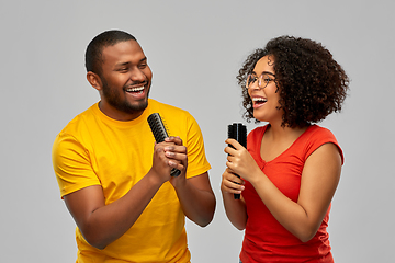 Image showing happy african couple singing to hairbrushes