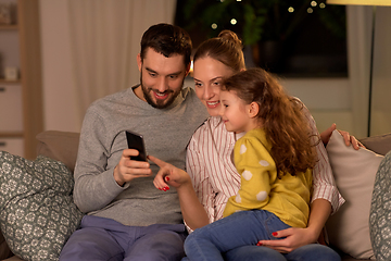 Image showing happy family with smartphone at home at night