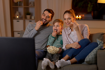 Image showing happy family with popcorn watching tv at home