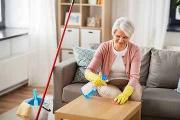 Image showing senior woman with detergent cleaning table at home