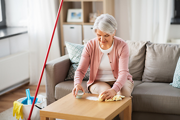 Image showing senior woman cleaning table with soda at home