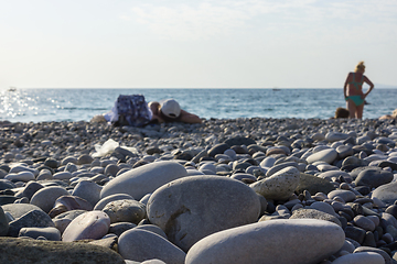 Image showing Tourists tan on pebble beach at a seaside resort under hot tropical sun