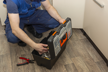 Image showing Plumber service worker digging in a toolbox at work in kitchen