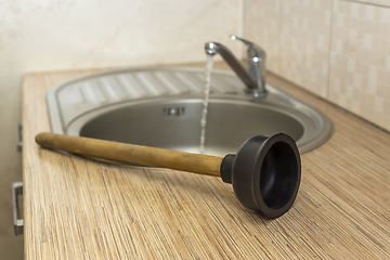 Image showing Household plumbing tool for clearing blockages is a plunger at the kitchen sink