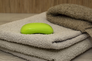 Image showing Body wash and a bar of green soap on a terry towel in bath