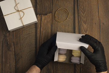 Image showing Hands in black gloves pack marshmallows in box in food delivery service