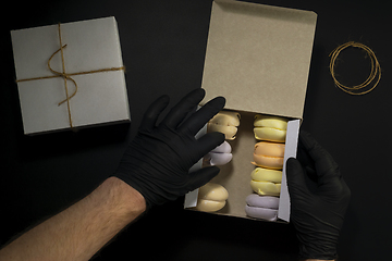 Image showing Hands in black gloves put marshmallows in box in food delivery service