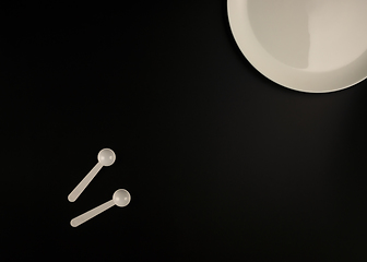 Image showing White plate and white spoons on black background