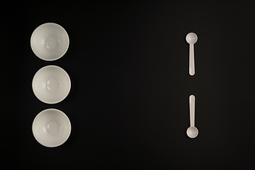 Image showing White cups and white spoons on black background