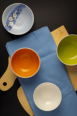 Image showing Empty bowls on waffle towel and cutting board on black background