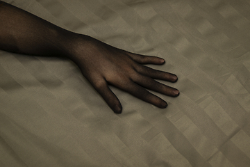 Image showing Graceful female hand in seductive nylon glove on bedsheet