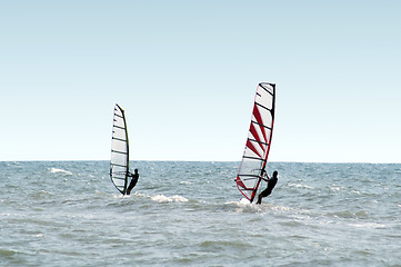 Image showing Two windsurfers on waves of a sea 