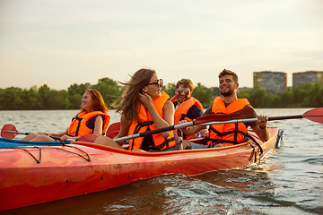 Image showing Happy friends kayaking on river with sunset on the background